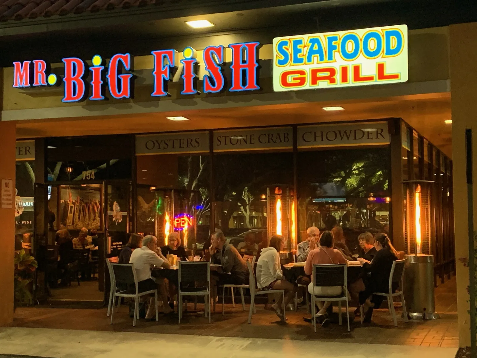 Mr. Big Fish Seafood Grill patio tables at night on Neapolitan Way